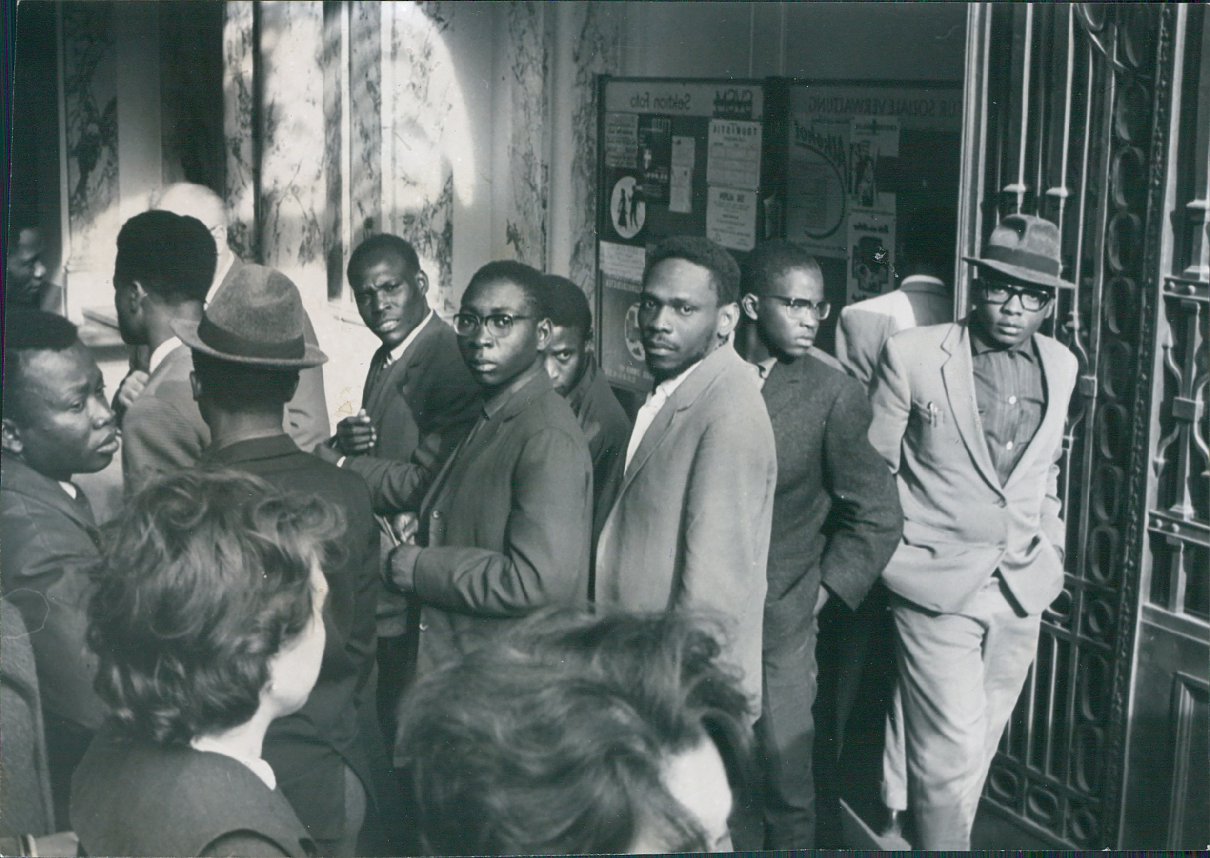 Eine Gruppe von Männern stehen im Foyer eines repräsentativen Gebäudes.