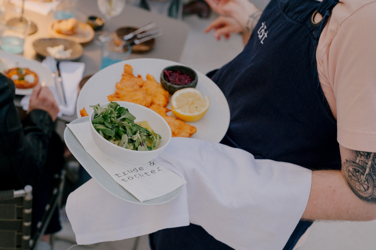 Kellner serviert Wiener Schnitzel mit Salat und Zitrone